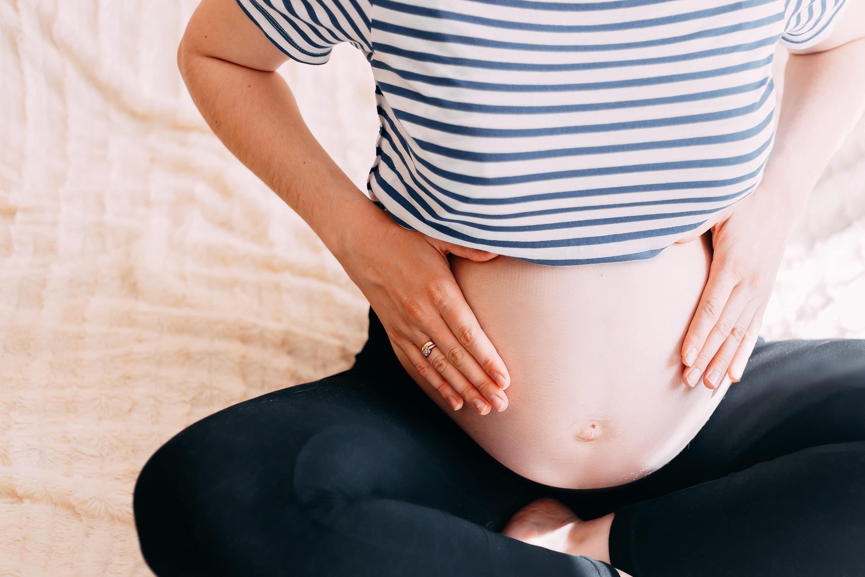 Pregnant Woman Belly. Pregnancy Concept. In living room. Pregnant tummy close up